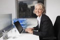 Portrait of smiling senior businesswoman using laptop at desk in office Royalty Free Stock Photo