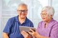 Portrait of smiling senior couple with eyeglasses using electronic tablet while relaxing at the bed room Royalty Free Stock Photo