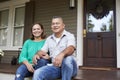 Portrait Of Smiling Senior Couple Sitting In Front Of Their Home Royalty Free Stock Photo