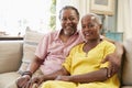 Portrait Of Smiling Senior Couple Sitting On Sofa At Home Royalty Free Stock Photo