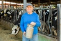 Senior farmer standing in cowshed at dairy farm wth milk churn Royalty Free Stock Photo