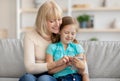 Happy mature woman and granddaughter using cellphone Royalty Free Stock Photo