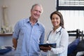 Portrait of smiling senior male patient and female therapist discussing file Royalty Free Stock Photo