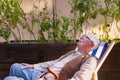 Portrait of smiling senior man resting after taking care vegetable plants in urban garden.