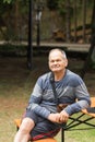 Portrait of smiling senior man sitting and resting on the park bench. Happy old man walking and spends time at the park. Royalty Free Stock Photo