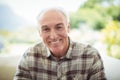 Portrait of smiling senior man sitting on sofa in living room Royalty Free Stock Photo