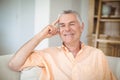 Portrait of smiling senior man sitting on sofa in living room Royalty Free Stock Photo