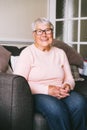 Portrait of smiling senior, mature retired grandmother in eyeglasses, elderly woman smiling sitting on sofa at home Royalty Free Stock Photo