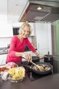 Portrait of smiling senior woman cooking food in kitchen Royalty Free Stock Photo