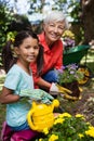 Portrait of smiling senior woman and girl watering flowers