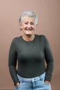 Portrait of smiling senior woman with hands in pockets in studio. Royalty Free Stock Photo