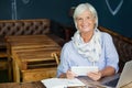 Portrait of smiling senior woman holding digital tablet while sitting at table Royalty Free Stock Photo