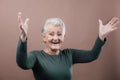 Portrait of smiling senior woman with raised arms in studio. Royalty Free Stock Photo