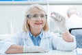 Portrait of smiling senior woman scientist analyzing pill in hand Royalty Free Stock Photo