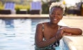 Portrait Of Smiling Senior Woman On Summer Holiday Relaxing In Swimming Pool Royalty Free Stock Photo