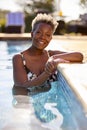 Portrait Of Smiling Senior Woman On Summer Holiday Relaxing In Swimming Pool Royalty Free Stock Photo