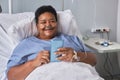 Smiling senior woman using phone while laying on bed in hospital room Royalty Free Stock Photo