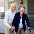 He always there to help. Portrait of a smiling senior woman using a walker with her husband beside her outside their Royalty Free Stock Photo