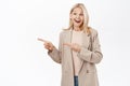 Portrait of smiling senior woman, 50 years old lady in trench coat, pointing finger left, looking happy and healthy Royalty Free Stock Photo