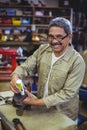 Portrait of smiling shoemaker applying glue on shoe