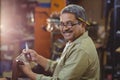 Portrait of smiling shoemaker cutting a piece of leather