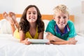 Portrait of smiling siblings with digital tablet lying on bed Royalty Free Stock Photo
