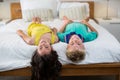 Portrait of smiling siblings lying on bed in bedroom Royalty Free Stock Photo