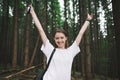 Portrait of a smiling sincere female tourist raising her hands up, holding smartphone, feeling successful, happy and free. Royalty Free Stock Photo
