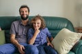 Smiling father and young son sitting together on their sofa Royalty Free Stock Photo