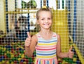 Smiling small girl showing thumbs up on indoor Royalty Free Stock Photo