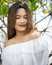 Portrait of a smiling Southeast Asian girl in a white dress with a blurred background of nature