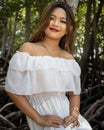 Portrait of a smiling Southeast Asian girl in a white dress with a blurred background of nature