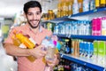 Portrait of man customer who is standing with drinks in supermarket. Royalty Free Stock Photo