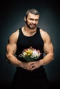 portrait of smiling sportive man with bouquet of flowers in hands