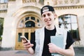 Portrait of a smiling student using a mobile phone and holds a notebook on the background of the university building. Royalty Free Stock Photo