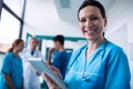 Portrait of smiling surgeon using digital tablet in corridor Royalty Free Stock Photo