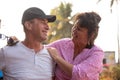 Portrait of smiling tanned middle-aged couple of woman and man sitting closely outside, embracing looking at each other. Royalty Free Stock Photo