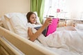 Portrait of smiling teen girl using digital tablet at bed Royalty Free Stock Photo