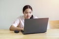 Portrait of smiling teenage Asian girl with disability using computer at home while studying online