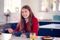 Portrait Of Smiling Teenage Girl Wearing School Uniform In Kitchen Eating Healthy Breakfast Royalty Free Stock Photo