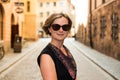 Portrait of a smiling thirty year old white woman with a black dress and sunglass in the Sunny Streets of Stockholm Old Town Royalty Free Stock Photo