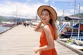 Portrait of smiling tourist woman walking on wooden pier where travel by ferry or rented boat or yacht to explore warm tropical Royalty Free Stock Photo