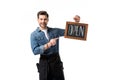 portrait of smiling waiter pointing at open blackboard in hand