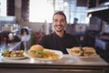 Portrait of smiling waiter serving fresh food at counter Royalty Free Stock Photo