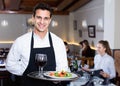 Portrait of smiling waiter with serving tray meeting restaurant guests Royalty Free Stock Photo