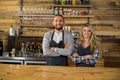 Portrait of smiling waiter and waitress standing with arms crossed at counter Royalty Free Stock Photo