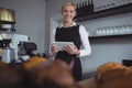 Portrait of smiling waitress holding digital tablet at counter Royalty Free Stock Photo