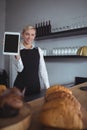 Portrait of smiling waitress holding digital tablet at counter Royalty Free Stock Photo