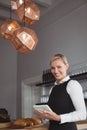 Portrait of smiling waitress holding digital tablet at counter Royalty Free Stock Photo