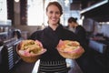 Portrait of smiling waitress serving fresh burgers at coffee shop Royalty Free Stock Photo